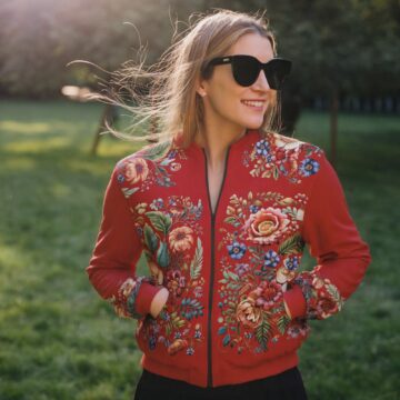 Czerwona bomberka w kwiaty z haftopodobnym wzorem, kieszeniami i czarną podszewką – styl i funkcjonalność w jednym.